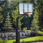 Dominator 72 inch adjustable basketball hoop with tempered glass backboard installed on a backyard court