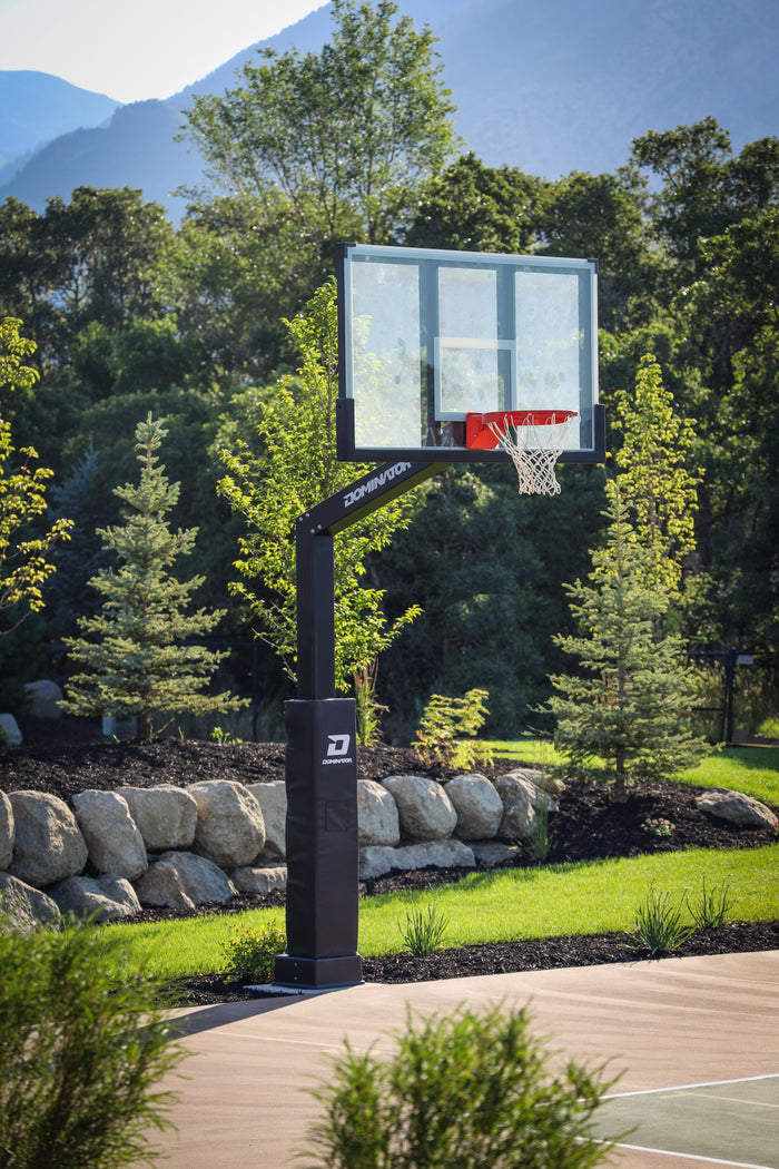 Dominator 72 inch adjustable basketball hoop with tempered glass backboard installed on a backyard court