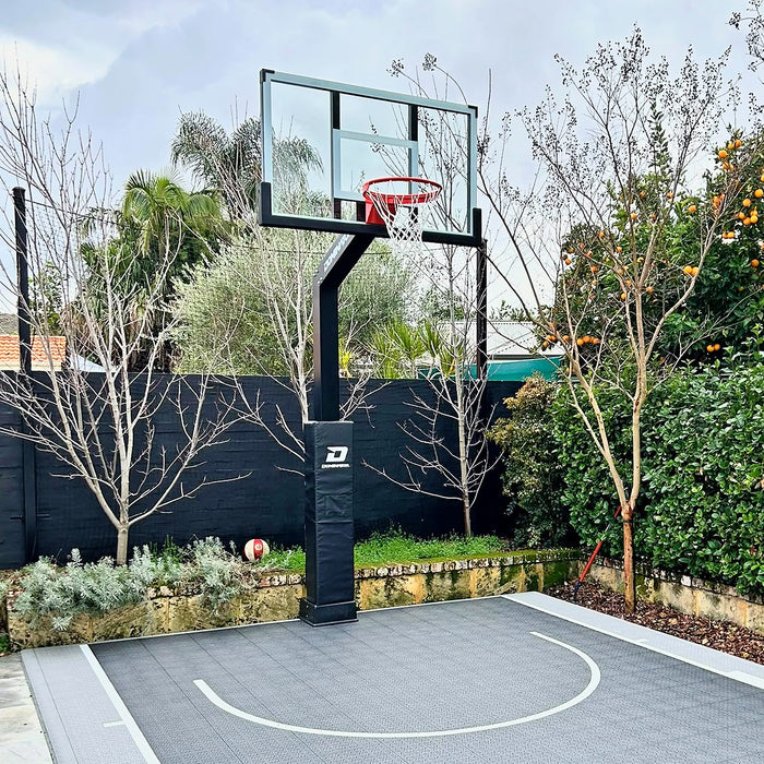 Dominator 54 inch adjustable basketball hoop in black installed on a backyard court